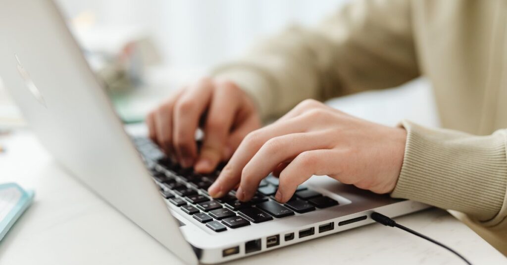 Person typing on a laptop keyboard while working online, representing digital productivity and technology