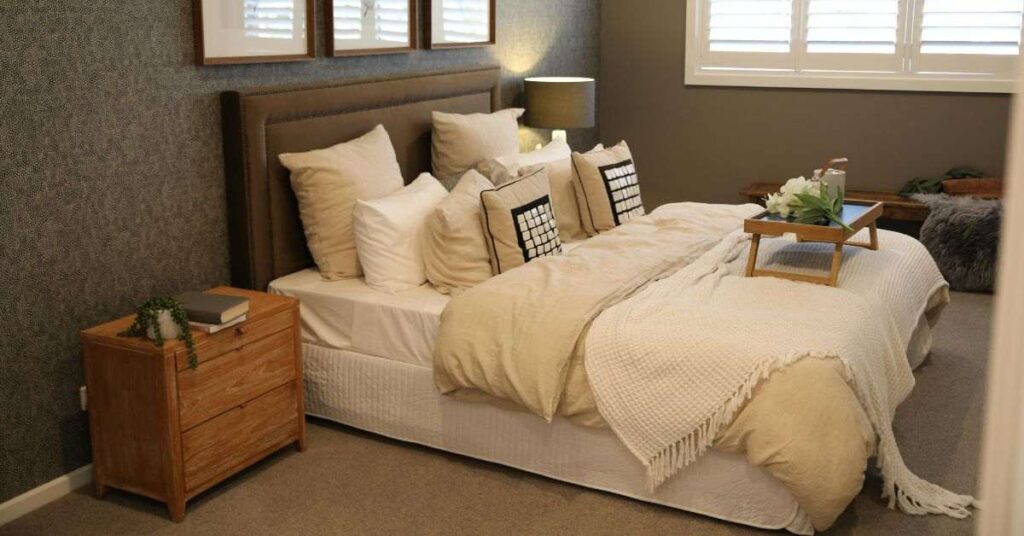Cozy modern bedroom with neutral bedding, wooden furniture, soft lighting, and elegant decor accents.