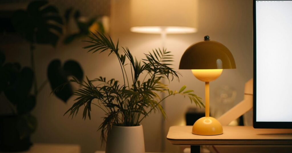 Warm modern workspace with a stylish desk lamp, indoor plants, and soft ambient lighting.