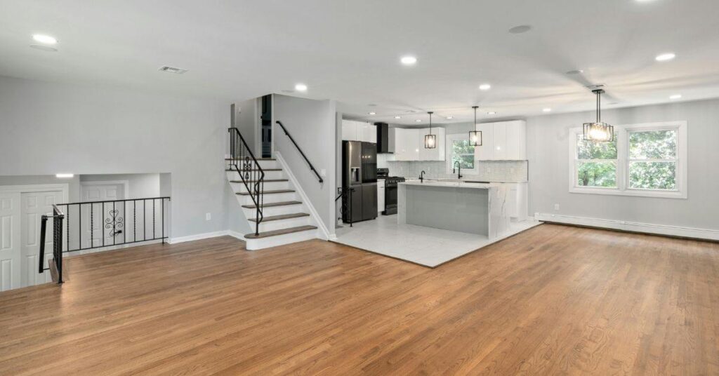 Bright open-concept home interior with hardwood floors, modern kitchen, staircase, and spacious living area.