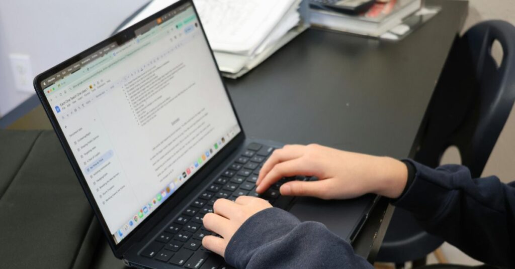 Person typing on a laptop while writing a blog article, creating digital content, and editing online documents